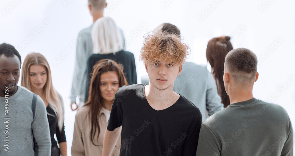 serious woman standing in front of casual group of young people serious woman standing in front of casual group of young people