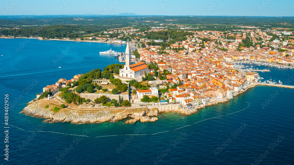 Town of Rovinj with high tower of St. Euphemia church. Croatian town buildings with red roofs on peninsula surrounded by Adriatic sea. Aerial panorama
