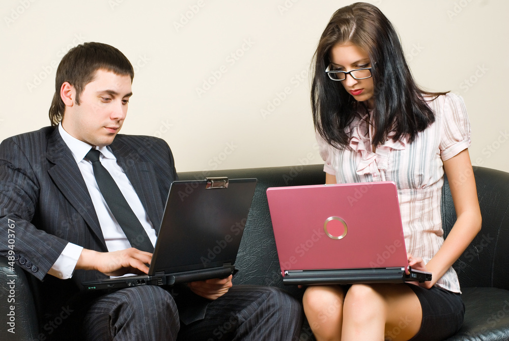 Businesspeople with laptops sitting on sofa