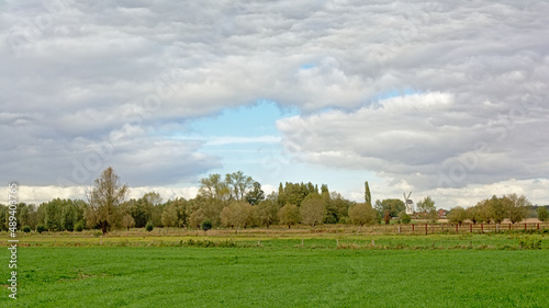 Lush green fields with trees under grey storm clouds in Oude Kalevallei nature reserve, Vinderhoute, Flanders, Belgium 