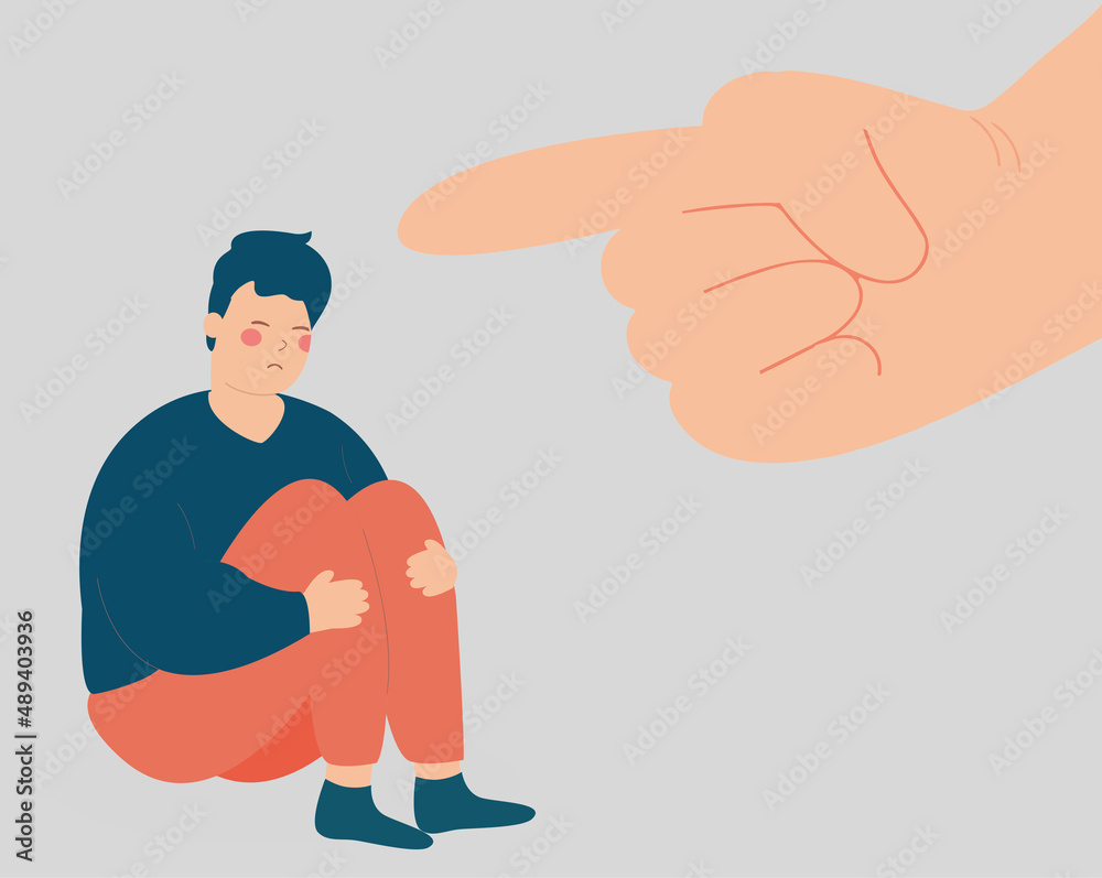 Sad young man suffers from violence and bullying from people. Stressed boy victime of abuse sits on the floor while a big finger is pointing at him. psychological violence, public censure concept.