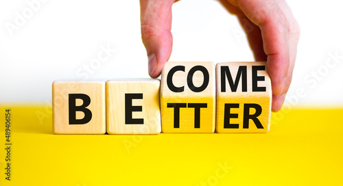 Become better symbol. Businessman turns wooden cubes and changes the concept word Better to Become. Beautiful yellow table white background. Business become better concept. Copy space. photo