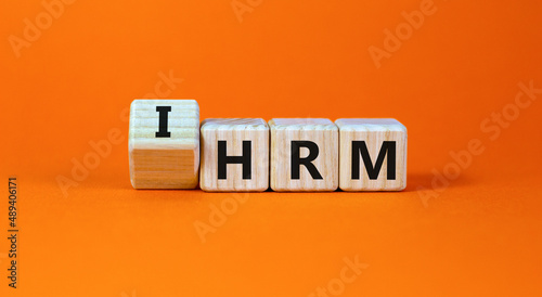 IHRM, international human resource management HRM symbol. Words IHRM, international human resource management on cubes on a orange background. Businessman hand. Business, IHRM HRM concept. Copy space.