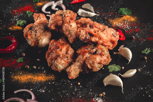 Fried chicken legs, breaded, with spices and herbs, on a dark background, horizontal, no people, selective focus, toned.