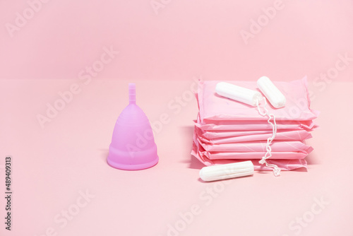 Menstrual cycle. Alternative means of hygiene and protection in critical days for women. Sanitary pads, tampons and silicone menstrual cup on pink background. Selective focus. Copy space