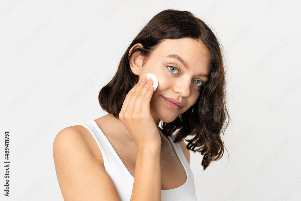 Teenager Ukrainian girl isolated on white background with cotton pad for removing makeup from her face Teenager Ukrainian girl isolated on white background with cotton pad for removing makeup from her face