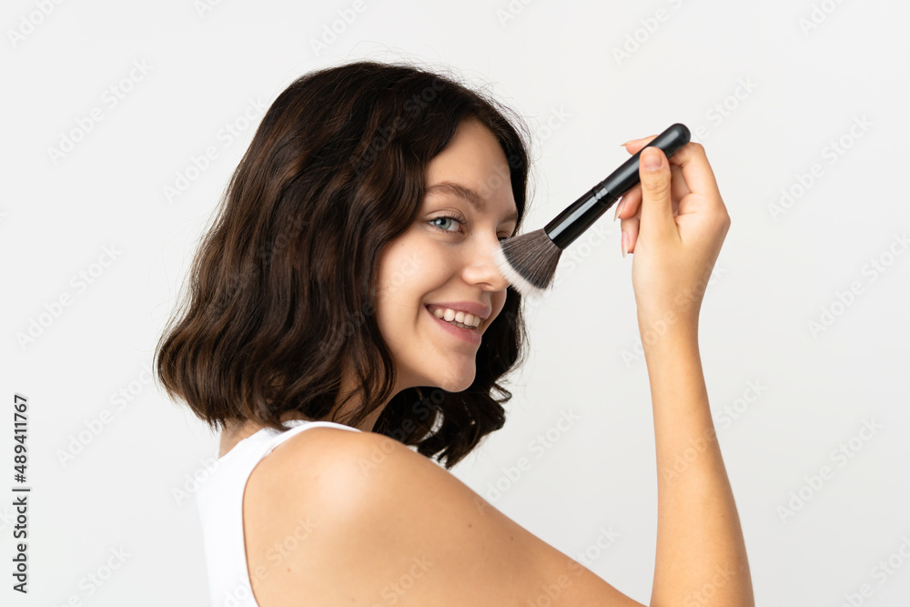 Teenager Ukrainian girl isolated on white background holding makeup brush and whit happy expression Teenager Ukrainian girl isolated on white background holding makeup brush and whit happy expression