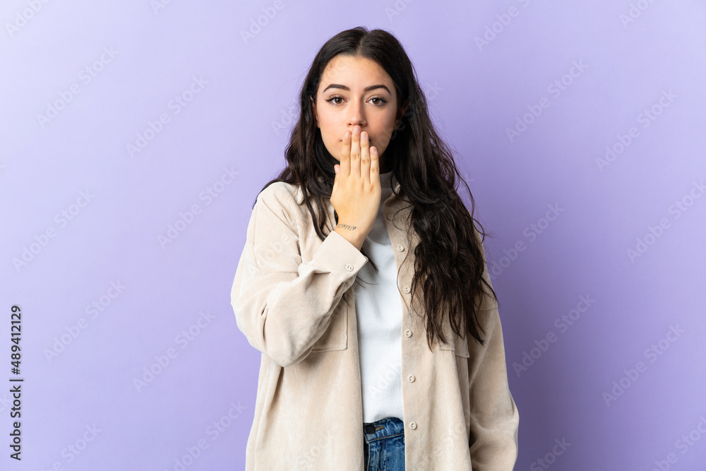 Young caucasian woman isolated on purple background covering mouth with hand