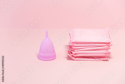 Menstrual cycle. Alternative means of hygiene and protection in critical days for women. Sanitary pads, or silicone menstrual cup on a pink background. Сoncept : reuse, eco, safety. Selective focus. 