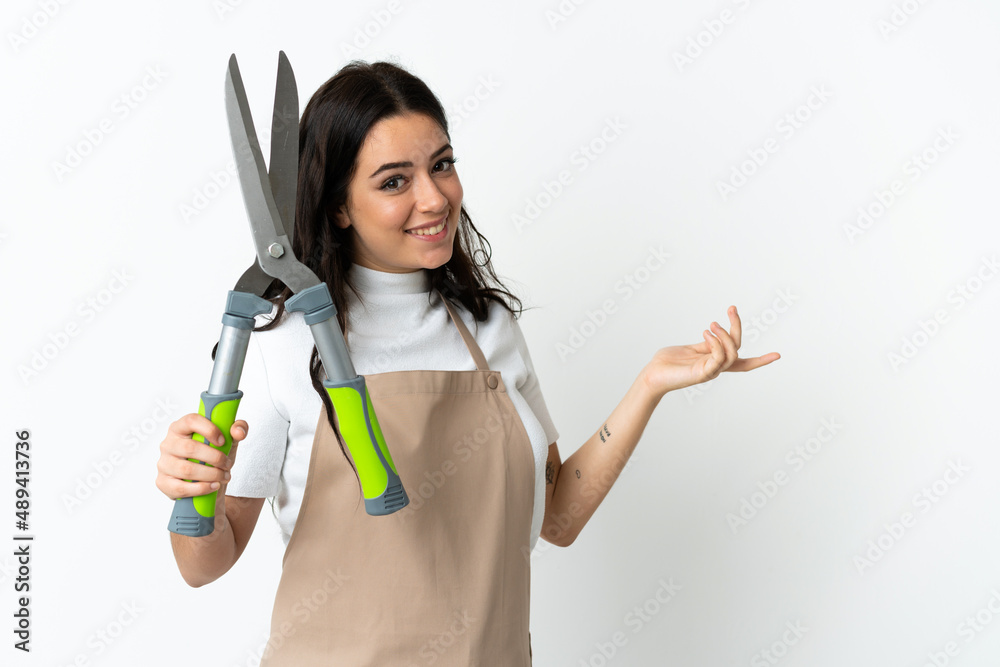Young caucasian woman holding a plant isolated on white background extending hands to the side for inviting to come Young caucasian woman holding a plant isolated on white background extending hands to the side for inviting to come
