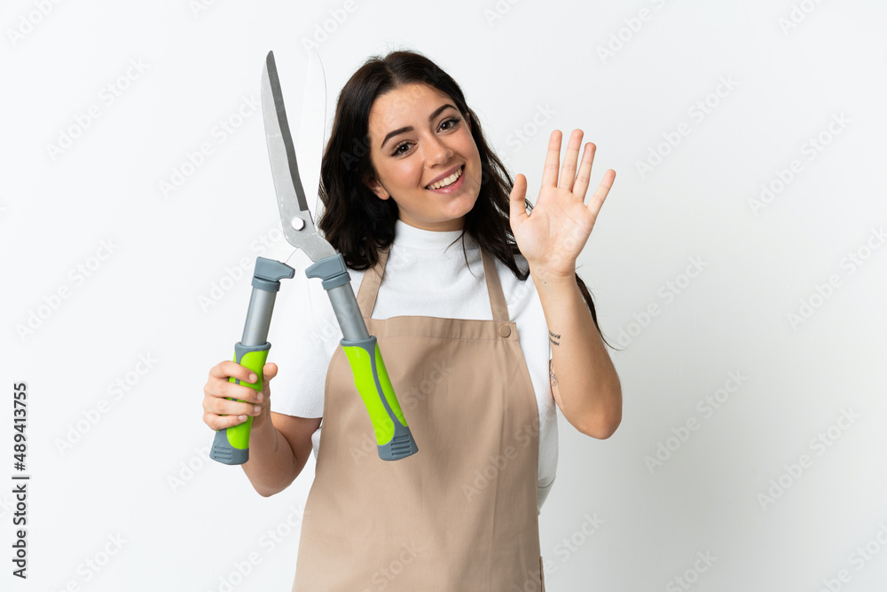 Young caucasian woman holding a plant isolated on white background saluting with hand with happy expression Young caucasian woman holding a plant isolated on white background saluting with hand with happy expression