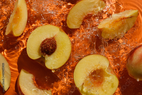 Cut peaches with splashing water on orange
