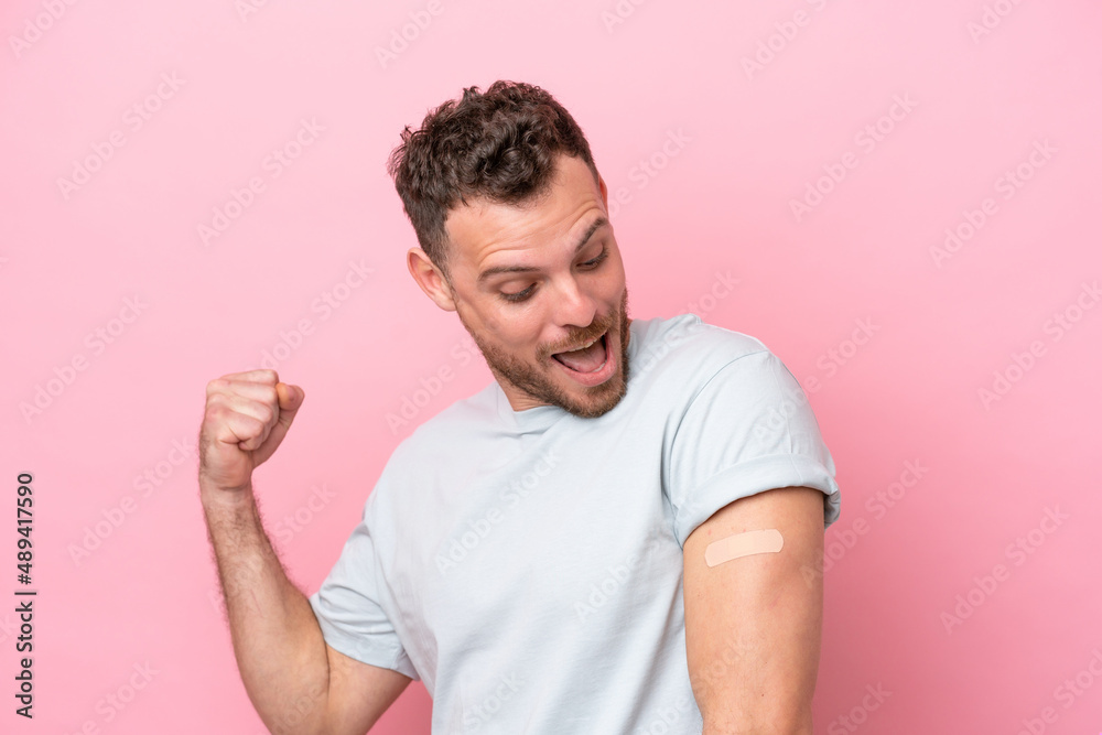 Young Brazilian man wearing a band-aids isolated on pink background celebrating a victory Young Brazilian man wearing a band-aids isolated on pink background celebrating a victory