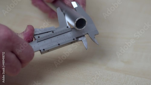 Close up view of a man measuring an aluminum pipe with an electronic calipers. Sweden. photo