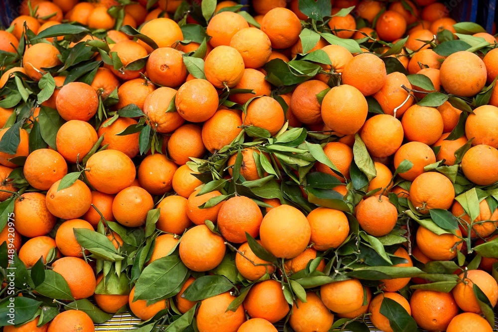 Background texture of orange fruit with green leaves. Oranges on the counter. High quality photo