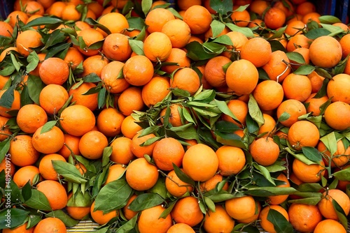 Background texture of orange fruit with green leaves. Oranges on the counter. High quality photo