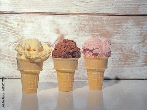 Three Ice Cream cones, Vanilla, Chocolate and Strawberry against a rustic wooden background with copy space.