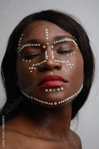 Close-up of beautiful African black woman with pearls on her face. Vertical.