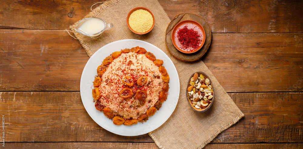 Couscous on almond milk with dried fruits and nuts on a table on a napkin next to milk and saffron. Couscous on almond milk with dried fruits and nuts on a table on a napkin next to milk and saffron.