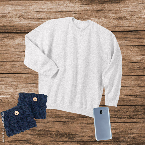 Mockup sweatshirt oatmeal color fashion clothing on a wood background with copyspace or room for text with knitted boot cuffs and cell phone.