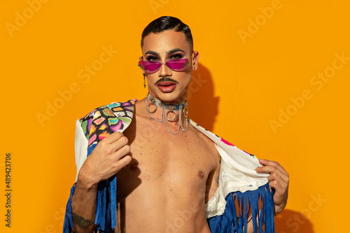 young drag queen in colorful dress on yellow background