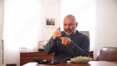 A diabetic man testing his blood sugar at home.  A real person with Type 2 diabetes.