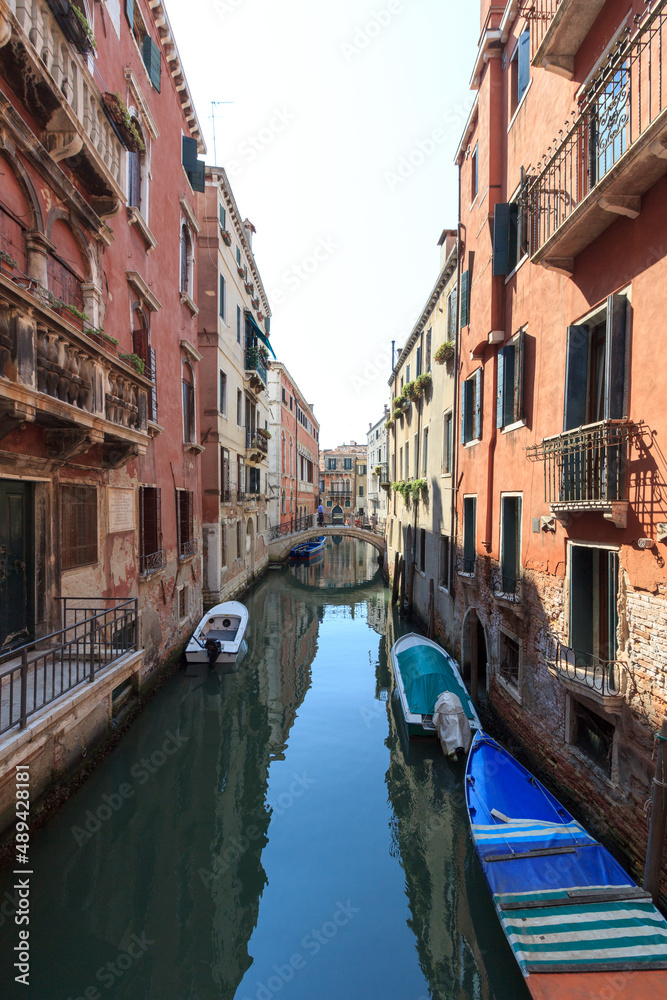 Small canal in Venice with boats and bridge, Italy