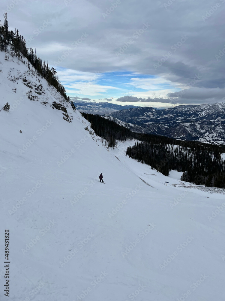 Scenic view of a snowboarder on the slopes of Big Sky Ski Resort in montana on a cloudy winter day