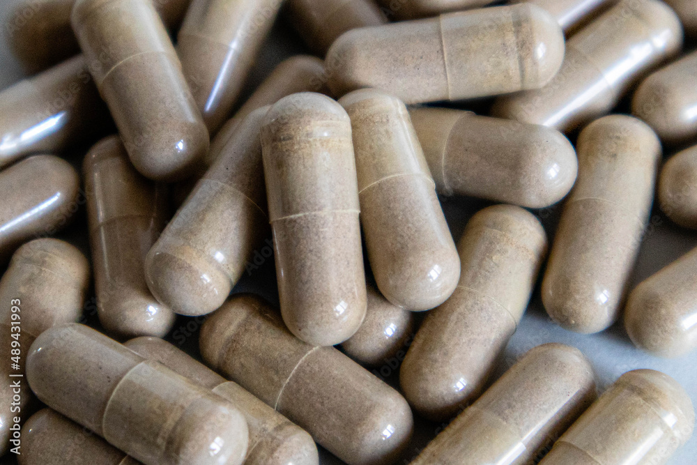 A scattering of brown capsules in close-up on a light background. A scattering of brown capsules in close-up on a light background.