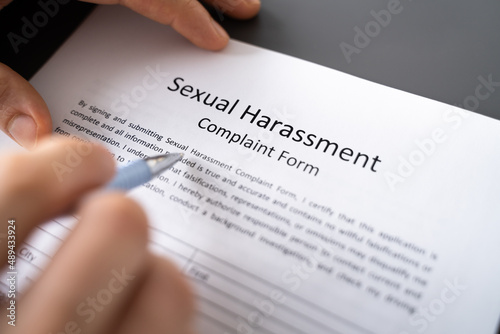 Human Hand Filling Sexual Harassment Complaint Form With Pen