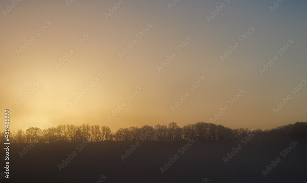 Morning sun nearly peaking over the ridge giving the sky an yellow to orange tint Morning sun nearly peaking over the ridge giving the sky an yellow to orange tint