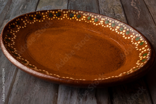 Traditional Mexican mud empty plate on a wooden table, concept of handmade Mexican crafts photo