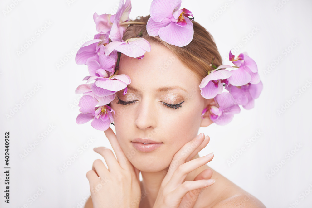 Enjoying the sensation of beauty. Studio shot of a gorgeous young woman with pink orchids in her hair. Enjoying the sensation of beauty. Studio shot of a gorgeous young woman with pink orchids in her hair.