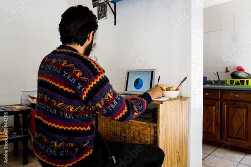 Unrecognizable man working from home, and eating breakfast. Lifestyle.