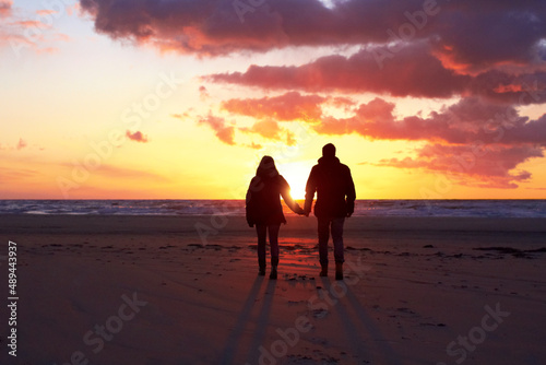 Shadows in the sunset. Silhouette of a couple going for a walk on the beach at sunset. © Fannie H/peopleimages.com