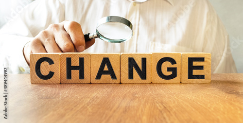 CHANGE inscription on the texture of wooden cubes. A business man holds a cube in his hand. An inscription on a financial, business or economic theme.