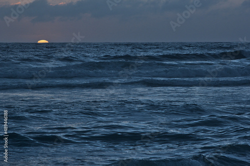 sol poneindose en el horizonte en el mar photo