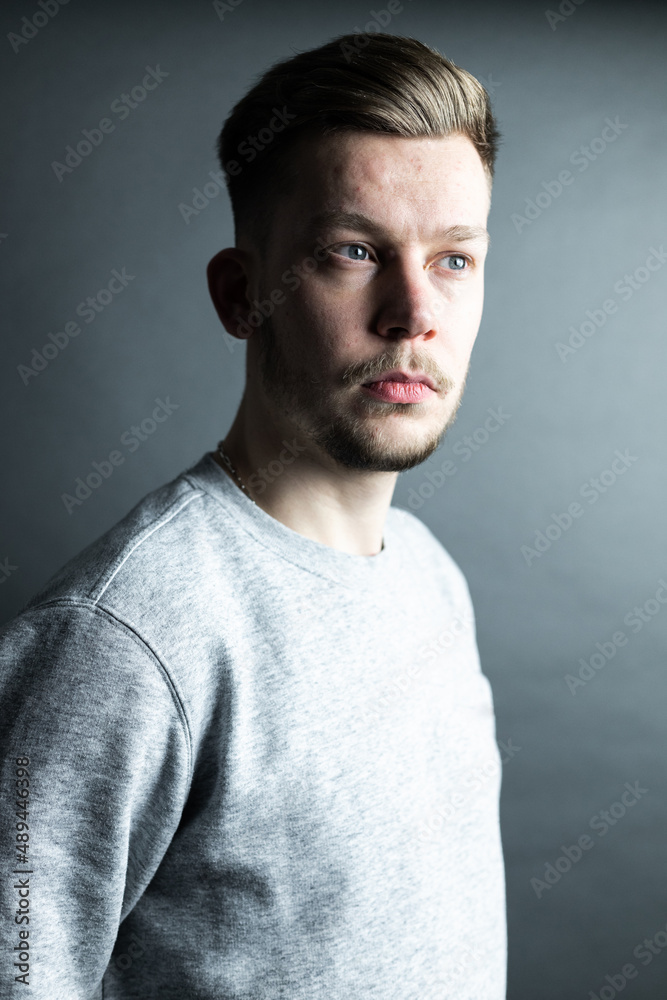 Fototapeta premium Junger Mann selbstbewusst Portrait vor grauem Hintergrund