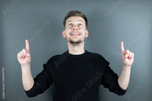 Junger Mann zeigt mit zwei Fingern nach oben Portrait