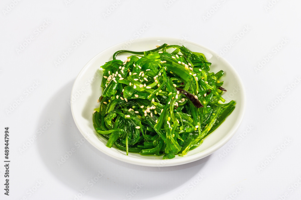 Chuka Seaweed Salad with sesame seeds isolated on white background. Trendy hard light, dark shadow Chuka Seaweed Salad with sesame seeds isolated on white background. Trendy hard light, dark shadow