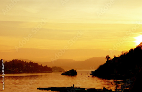 Bathed in gold. A panoramic shot of a lake with small pieces of land, during the sunset with tones of gold and orange.