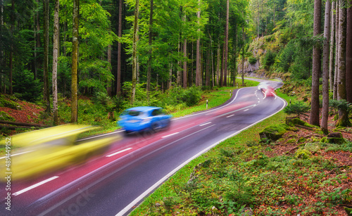 A road among the forest. Fast traffic. A blur of car lights. Landscape in eve...