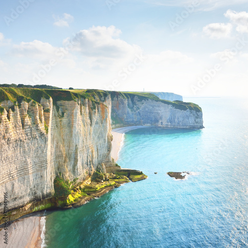 Picturesque panoramic aerial view of the Etretat white cliffs at sunset. Dramatic sky, azure water. Summer vacations in Normandy, France. Travel destinations, national landmark, sightseeing, history
