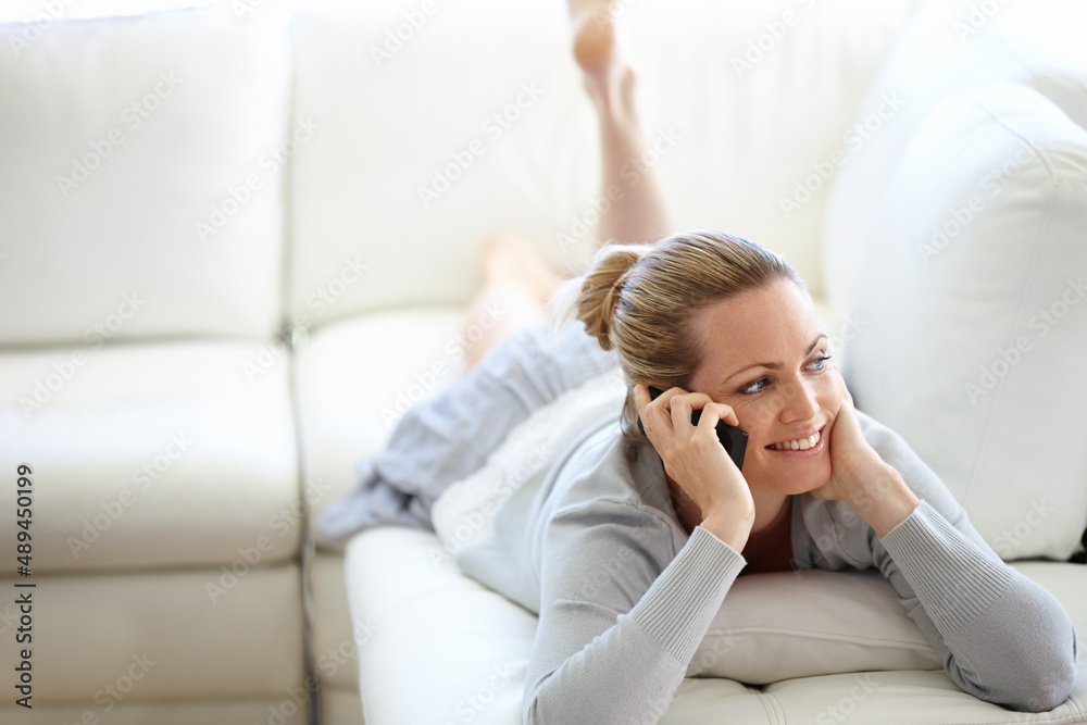 We could talk for hours. A happy young woman using her cellphone while casually lying on a couch. We could talk for hours. A happy young woman using her cellphone while casually lying on a couch.