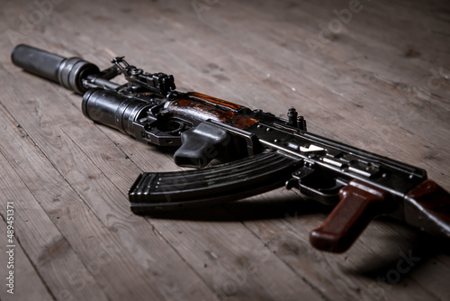 Kalashnikov assault rifle with suppressor isolated on wooden background photo