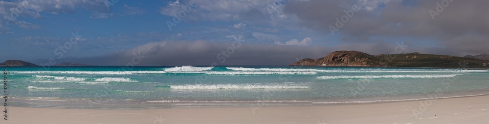 Panorama of sunny and idyllic white sand beach with no people and waves crashing in Esperance Bay, Western Australia.