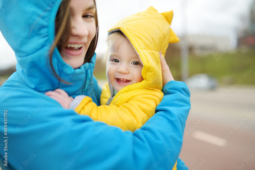 Cute big sister cuddling with her toddler brother. Adorable teenage girl holding baby boy