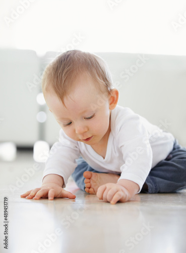 What is this. shot of a cute baby playing while sitting on the floor.
