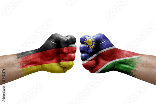 Two hands punch to each others on white background. Country flags painted fists, conflict crisis concept between germany and namibia