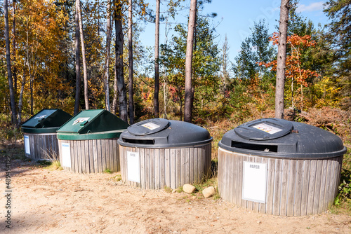 Row of recycling bins in a recycling centre in the countryside on a sunny autumn day. Autumn colours in background.